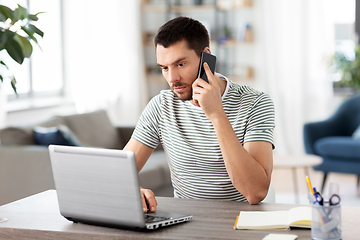 Image showing man with laptop calling on phone at home office