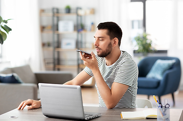 Image showing man with laptop calling on phone at home office