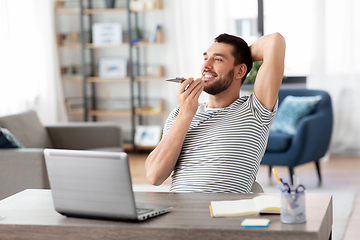 Image showing man with laptop calling on phone at home office