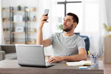 Image showing man with smartphone and laptop at home office
