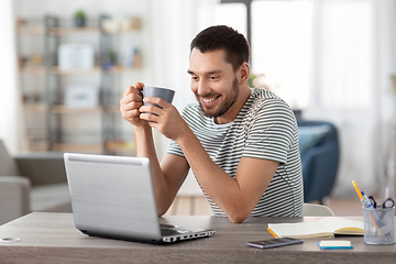 Image showing man with laptop drinking coffee at home office