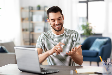 Image showing man using hand sanitizer at home office