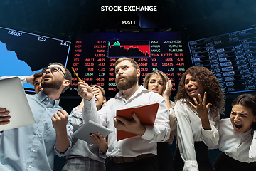 Image showing Nervous tensioned investors analyzing crisis stock market with charts on screen on background, falling stock exchange