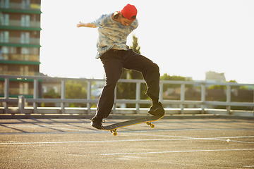 Image showing Skateboarder doing a trick at the city\'s street in summer\'s sunshine