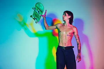 Image showing Skateboarder doing a trick isolated on studio background in colorful neon light