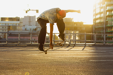 Image showing Skateboarder doing a trick at the city\'s street in summer\'s sunshine