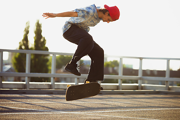 Image showing Skateboarder doing a trick at the city\'s street in summer\'s sunshine