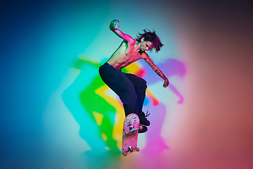 Image showing Skateboarder doing a trick isolated on studio background in colorful neon light