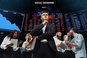 Image showing Nervous tensioned investors analyzing crisis stock market with charts on screen on background, falling stock exchange