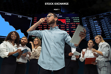 Image showing Nervous tensioned investors analyzing crisis stock market with charts on screen on background, falling stock exchange