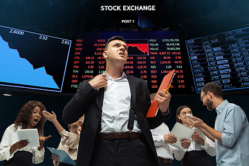 Image showing Nervous tensioned investors analyzing crisis stock market with charts on screen on background, falling stock exchange