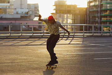 Image showing Skateboarder doing a trick at the city\'s street in summer\'s sunshine