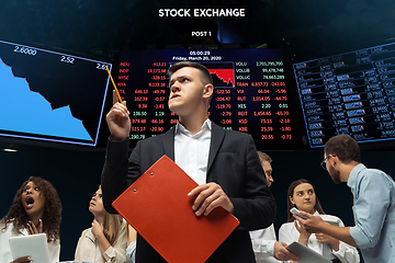 Image showing Nervous tensioned investors analyzing crisis stock market with charts on screen on background, falling stock exchange