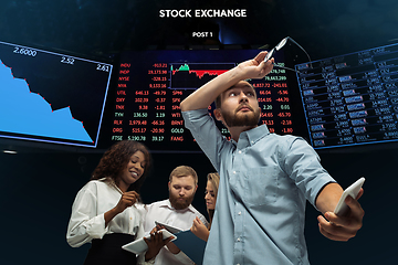 Image showing Nervous tensioned investors analyzing crisis stock market with charts on screen on background, falling stock exchange