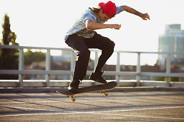 Image showing Skateboarder doing a trick at the city\'s street in summer\'s sunshine