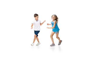 Image showing Happy little caucasian girl and boy jumping and running isolated on white background