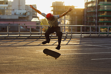 Image showing Skateboarder doing a trick at the city\'s street in summer\'s sunshine