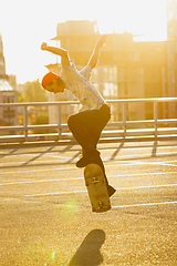 Image showing Skateboarder doing a trick at the city\'s street in summer\'s sunshine