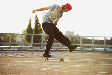 Image showing Skateboarder doing a trick at the city\'s street in summer\'s sunshine