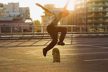 Image showing Skateboarder doing a trick at the city\'s street in summer\'s sunshine