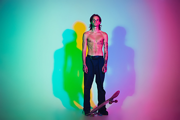 Image showing Skateboarder doing a trick isolated on studio background in colorful neon light