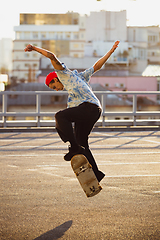 Image showing Skateboarder doing a trick at the city\'s street in summer\'s sunshine