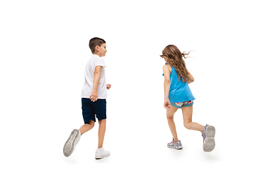 Image showing Happy little caucasian girl and boy jumping and running isolated on white background