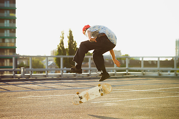 Image showing Skateboarder doing a trick at the city\'s street in summer\'s sunshine