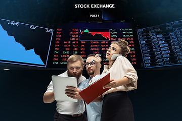 Image showing Nervous tensioned investors analyzing crisis stock market with charts on screen on background, falling stock exchange