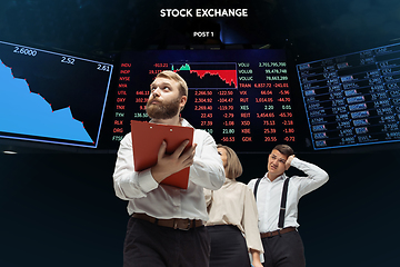 Image showing Nervous tensioned investors analyzing crisis stock market with charts on screen on background, falling stock exchange