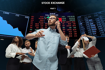 Image showing Nervous tensioned investors analyzing crisis stock market with charts on screen on background, falling stock exchange