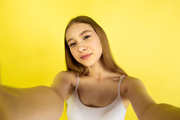 Image showing Caucasian young girl\'s portrait isolated on yellow studio background. Beautiful female model. Concept of human emotions, facial expression, sales, ad, youth culture.