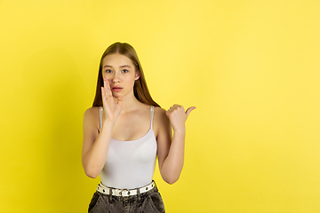 Image showing Caucasian young girl\'s portrait isolated on yellow studio background. Beautiful female model. Concept of human emotions, facial expression, sales, ad, youth culture.