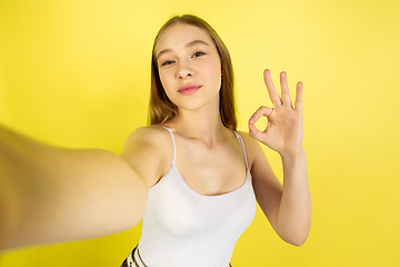 Image showing Caucasian young girl\'s portrait isolated on yellow studio background. Beautiful female model. Concept of human emotions, facial expression, sales, ad, youth culture.