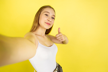 Image showing Caucasian young girl\'s portrait isolated on yellow studio background. Beautiful female model. Concept of human emotions, facial expression, sales, ad, youth culture.