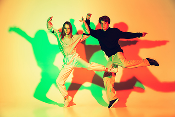 Image showing Young man and woman dancing hip-hop, street style isolated on studio background in neon light