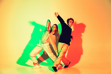 Image showing Young man and woman dancing hip-hop, street style isolated on studio background in neon light