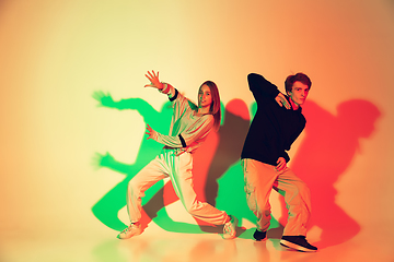Image showing Young man and woman dancing hip-hop, street style isolated on studio background in neon light