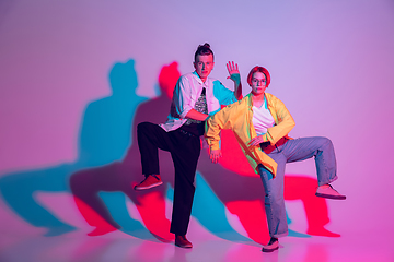 Image showing Young man and woman dancing hip-hop, street style isolated on studio background in neon light