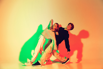 Image showing Young man and woman dancing hip-hop, street style isolated on studio background in neon light