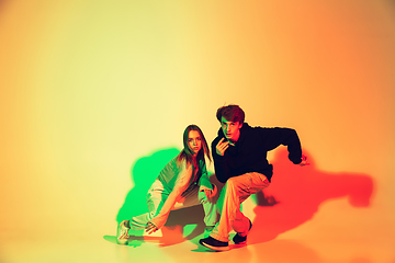 Image showing Young man and woman dancing hip-hop, street style isolated on studio background in neon light