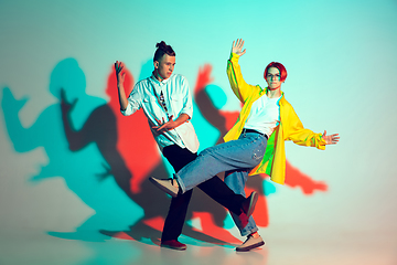 Image showing Young man and woman dancing hip-hop, street style isolated on studio background in neon light