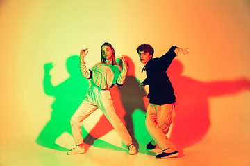 Image showing Young man and woman dancing hip-hop, street style isolated on studio background in neon light