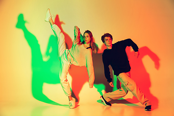 Image showing Young man and woman dancing hip-hop, street style isolated on studio background in neon light