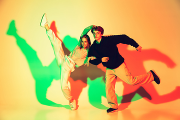 Image showing Young man and woman dancing hip-hop, street style isolated on studio background in neon light