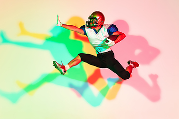 Image showing American football player isolated on gradient studio background in neon light with shadows