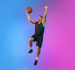 Image showing Young basketball player in motion on gradient studio background in neon light