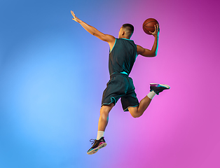 Image showing Young basketball player in motion on gradient studio background in neon light