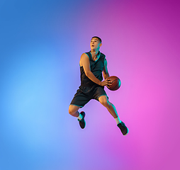 Image showing Young basketball player in motion on gradient studio background in neon light