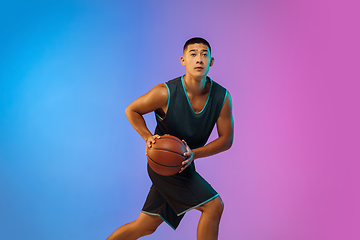 Image showing Young basketball player in motion on gradient studio background in neon light